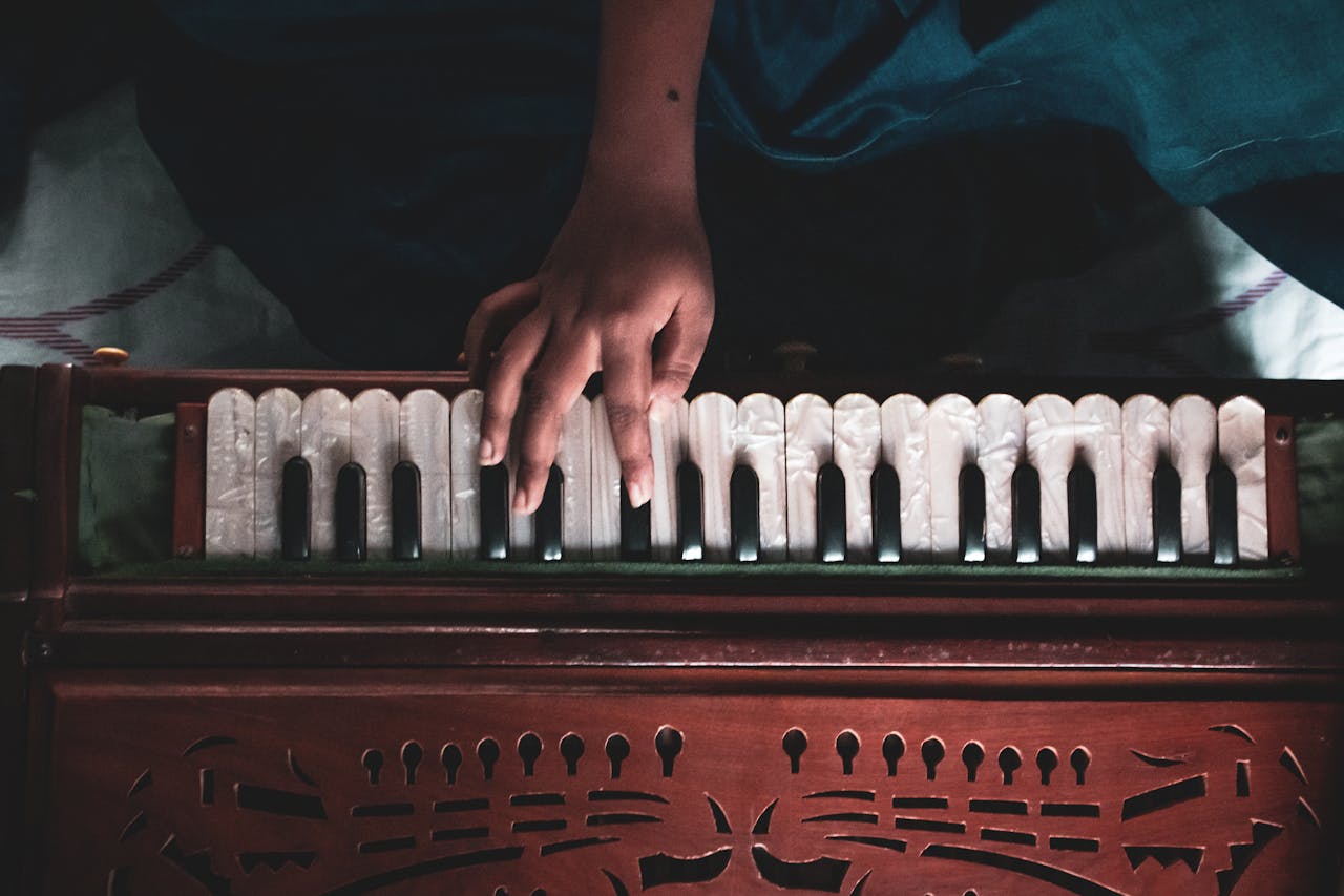 gallery-3 A hand playing a wooden harmonium, showcasing musical artistry.