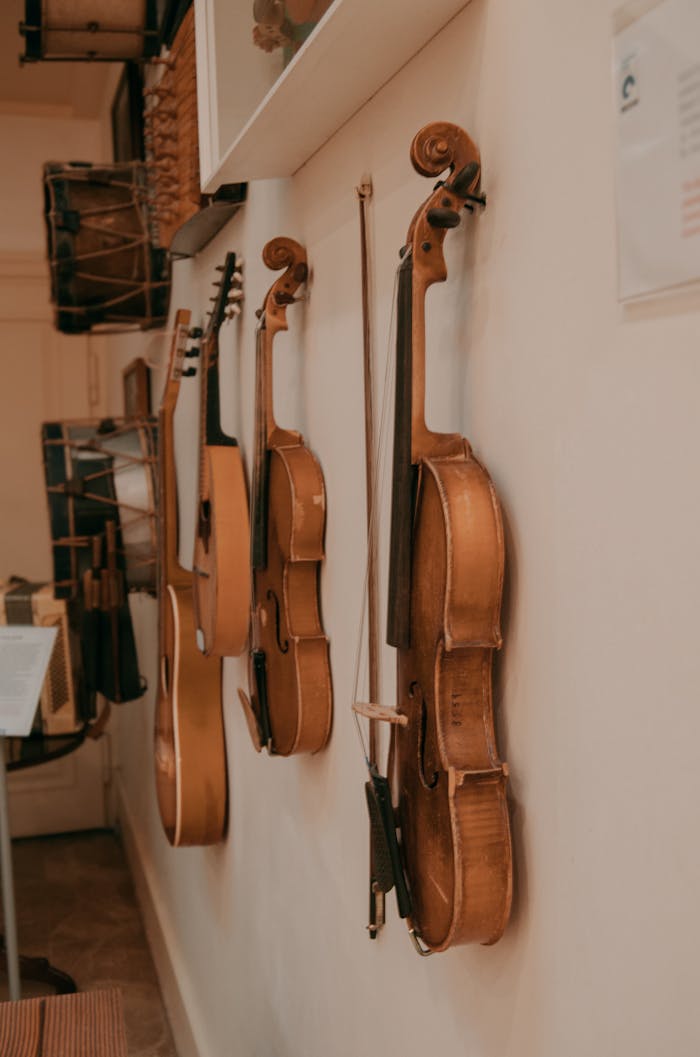 about-01 Collection of violins and guitars hanging on a wall in a music studio.