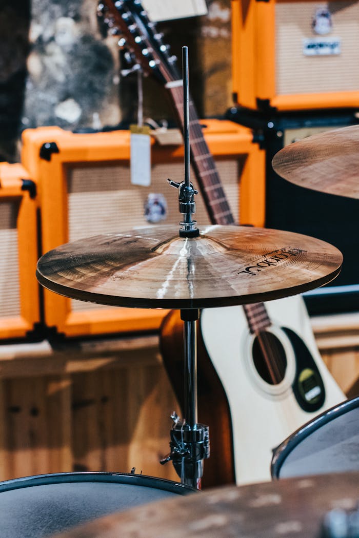 services-02 Close-up of cymbal with guitars and amplifiers in a music store setting.
