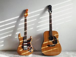 Home A minimalist scene featuring an acoustic and electric guitar against a white wall, perfect for music enthusiasts.