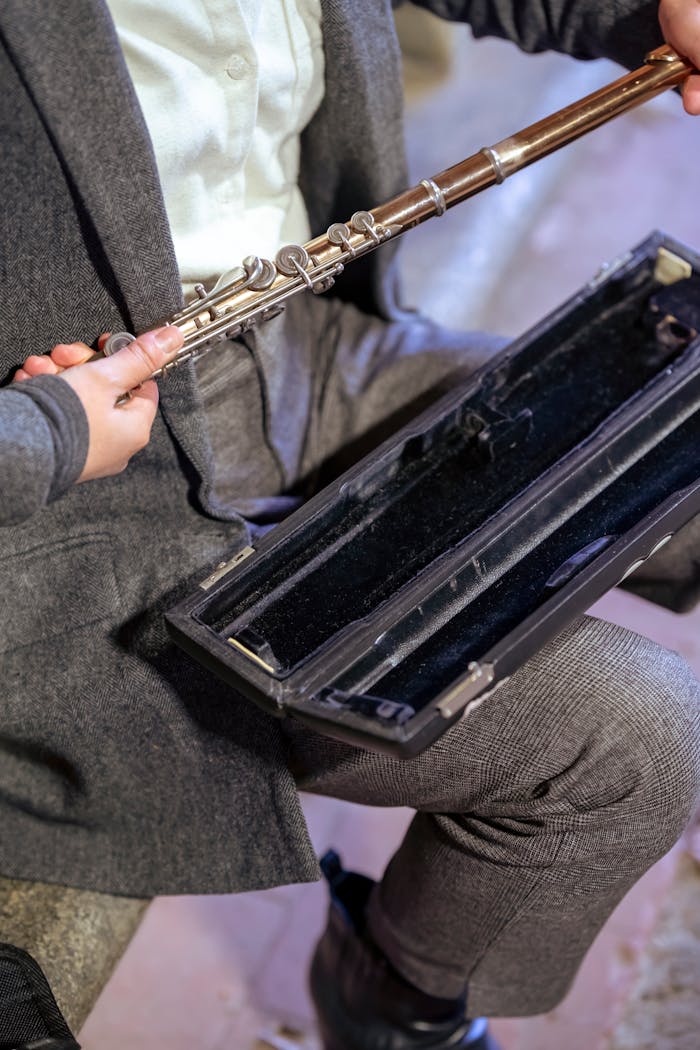 High angle of crop unrecognizable female musician taking musical instrument from case for street performance