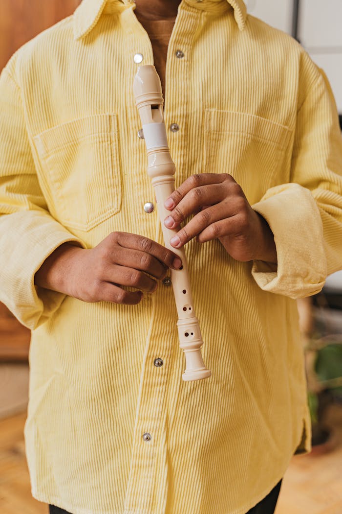 services-03 Close-up of hands holding a white recorder, wearing a yellow shirt indoors.